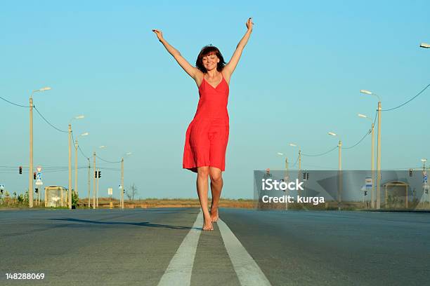 Photo libre de droit de Fille En Robe Rouge Marchez Pieds Nus Sur La Route Vide banque d'images et plus d'images libres de droit de Femmes