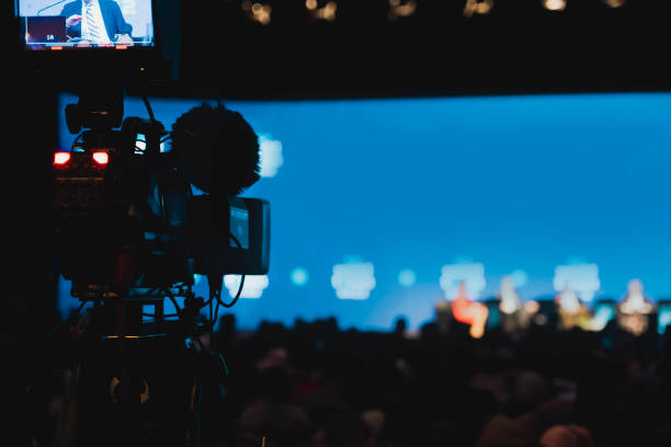 la telecamera collegata al veicolo di trasmissione in diretta ha la sua luce di conteggio accesa mentre i partecipanti stanno parlando a una conferenza internazionale trasmessa in diretta su un canale di notizie. - tv producer foto e immagini stock