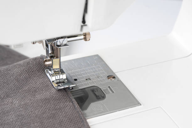 istock Modern sewing machine presser foot with gray fabric and thread, closeup 1482881511