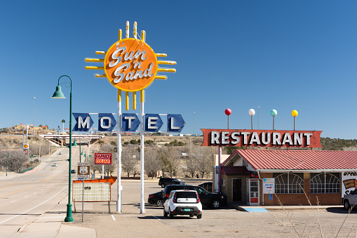San Rosa, New Mexico - USA: Sun 'n Sand Motel and Restaurant.  Bright orange and yellow sign is  superimposed on the Zia symbol. Background is vivid cloudless blue sky.