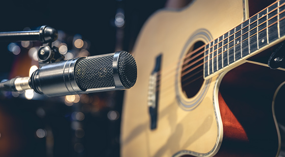 Acoustic guitar and microphone, close up, recording in a music studio.