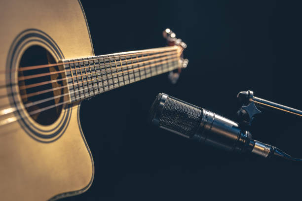 istock Acoustic guitar and microphone, recording in a music studio. 1482884795