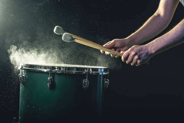 istock A man plays a musical percussion instrument with sticks on a dark background. 1482886074