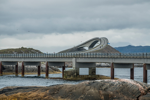 Great view on the the norwegian atlantic ocean road with the famous Storseisundet Bridge in the background and rocks in the foreground.