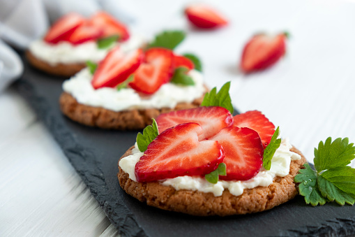 Healthy toast with strawberry, cream cheese and mint leaf. Tasty breakfast. Clean eating, dieting or recipe of healthy snack sandwich for vegetarian. Restaurant serving on slate board.