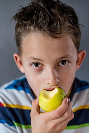 portrait of a boy holding a green apple and eating it