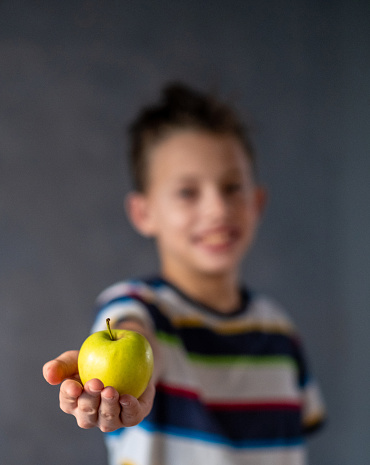 portrait of a boy holding an apple in front of him