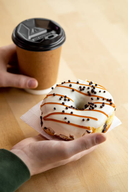 istock Appetizing donut and coffee in male hands, close-up. 1482887379