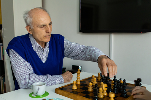 Senior man is playing chess in living room