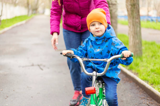 Little kid boy and his father in autumn park with a bicycle. Dad teaching his son biking. Active family leisure. Child with helmet on bike. Safety, sports, leisure with kids concept.