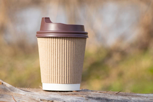 istock brown paper coffee cup stands in the forest on a sunny day 1482890190