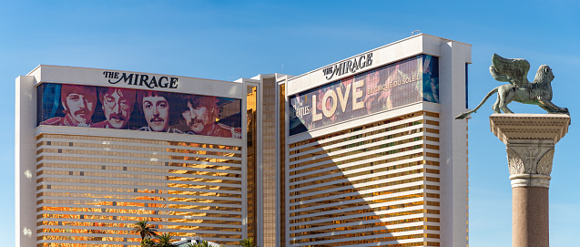 Las Vegas, United States - November 24, 2022: A picture of the Mirage with a large ad of the show Love by Cirque du Soleil, about the Beatles, on its facade. The Saint Theodore column, part of the Venetian Las Vegas is also on the right.