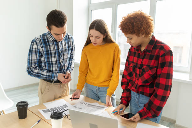 istock Teamwork brainstorm young professional team concept. Happy multiracial coworkers cooperating working together at office meeting. Diverse colleagues discussing project ideas editing documentation. 1482890735