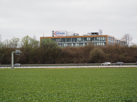 Munich, Bavaria, Germany - April 16 2023: Infineon Technologies AG Neubiberg Germany's largest semiconductor manufacturer headquarters building with blue logo.