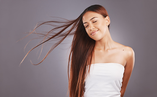 Salon, hair and hairstyle by woman with care, glow and healthy skincare isolated in a studio gray background. Young, skin and natural beauty model smile due to keratin treatment for haircare