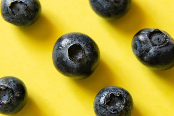 ripe blueberries on a yellow background close-up ripe blueberries on a yellow background close up dissert stock pictures, royalty-free photos & images