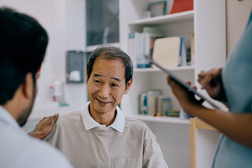 rear view of doctor tapping on shoulder of senior patient, giving encouragement