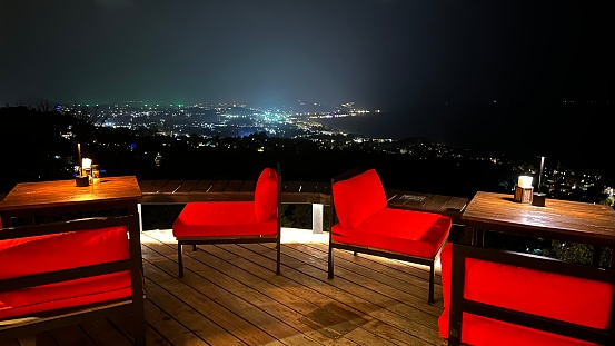 Rote Sesseln in einem Restaurant mit Blick auf die nächtliche Stadt