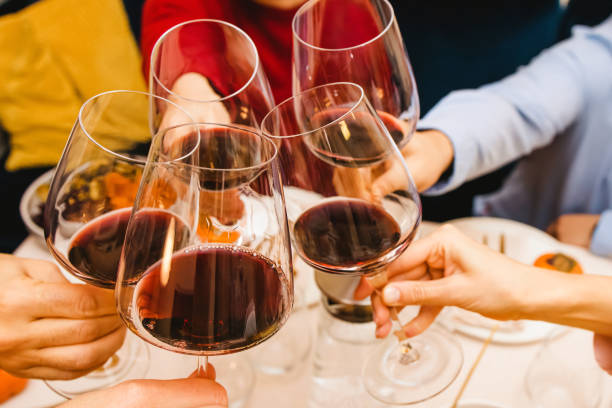 istock Hands clinking with a glasses filled with red wine sitting at the Thanksgiving dinner table. Celebration, gather, 1482898579