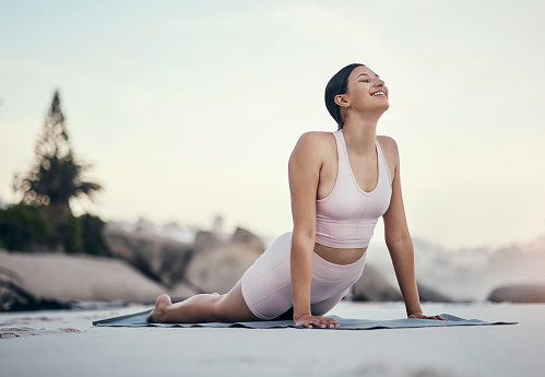 Stretching, yoga and woman on a beach floor for wellness, peace and zen, pose and balance on sky background. Meditation, stretch and girl relax with training, energy and peaceful, mindset or workout