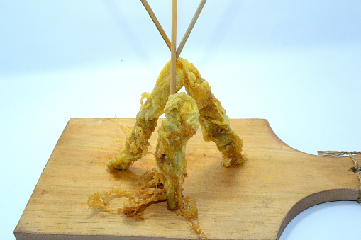 The egg rolls stand upright on a wooden plank