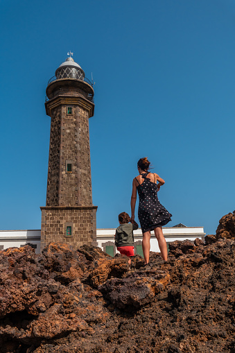 Mother and son visiting on vacation at the beautiful lighthouse of Orchilla in southwest El Hierro. Canary Islands