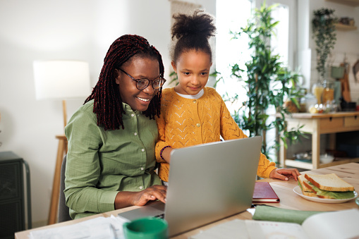 Mother and daughter using laptop at home