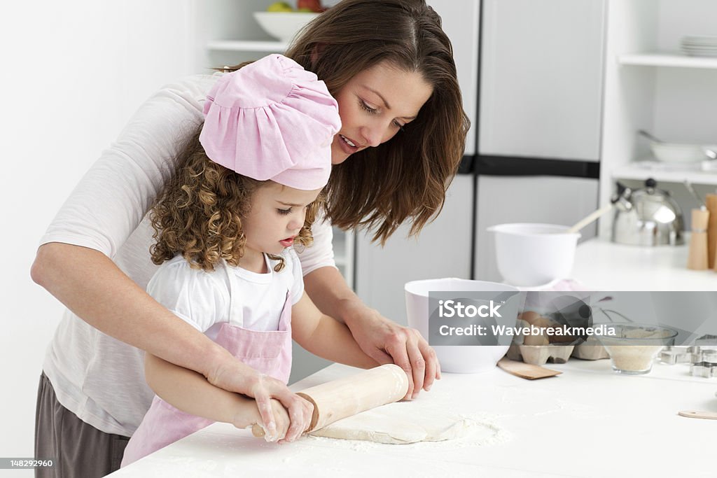 Mother and daughter using a rolling pin together Mother and daughter using a rolling pin together in the kitchen Adult Stock Photo