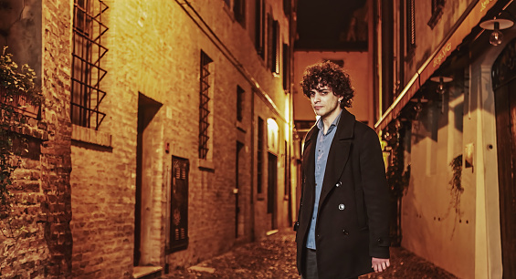 A furious young man stands in a dimly lit alleyway, his face contorted with anger and frustration.