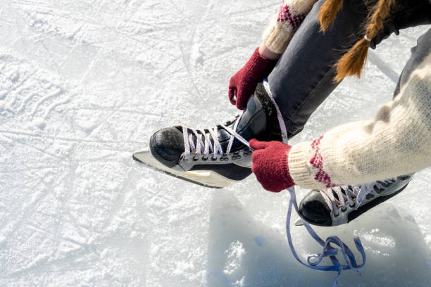 donna che lega i lacci delle scarpe del pattino da ghiaccio in primo piano - ice skates foto e immagini stock