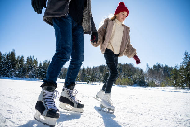 istock Daughter ice skating with father on lake 1482947407