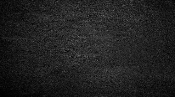 Black or dark gray rough grainy stone or sand texture background.