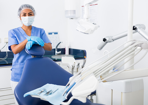Portrait of professional qualified woman dentist posing with arms crossed at modern dental clinic