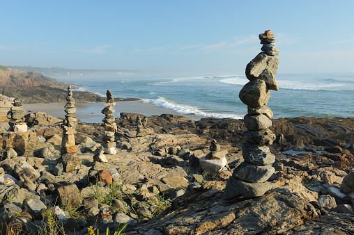 Small inukshuk monument inspired by the Inuit culture, made with rocks on a clear blue sky at sunrise