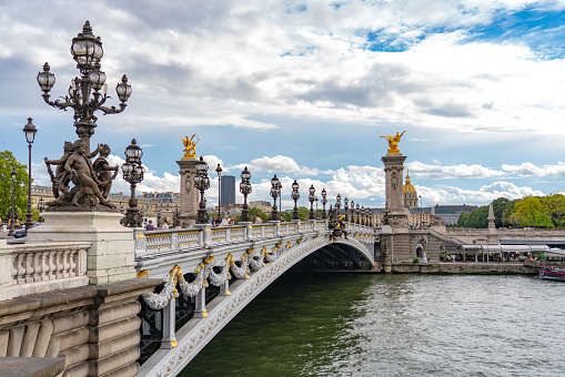 France, Paris - September 19, 2022: Pont Alexandre III bridge over river Seine. Bridge decorated with ornate Art Nouveau lamps and sculptures. The Alexander III Bridge across Seine river.