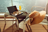 relax travel freelance working lifestyle ocean view balcony terrace with laptop and headphone remotely technology device arrange on rattan stool on wooden floor with sunshine morning light vacation