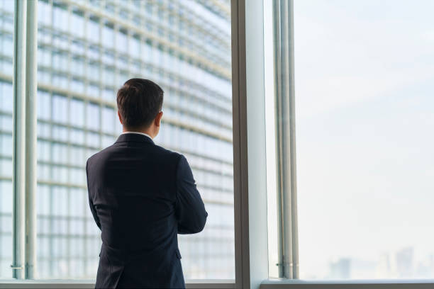 istock asian businessman standing by window looking at view 1482966302