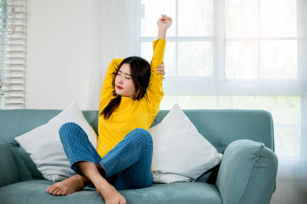 istock woman stretch oneself for relaxing activity feeling lazy on weekend on couch 1482967132