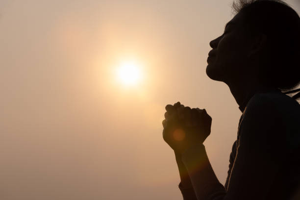 silueta de la mujer levantando sus manos en adoración, la mujer orando por dios, el fondo del concepto de religión cristiana. - heaven women sunrise inspiration fotografías e imágenes de stock