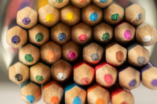 close up of various wooden colored pencils on beaker on desk