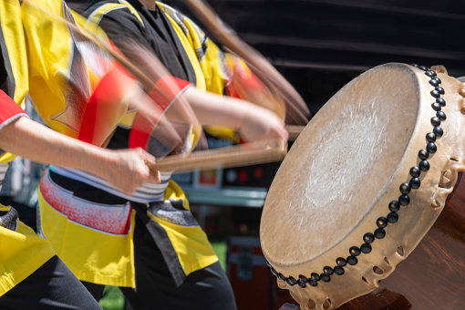Taiko drummers perform on stage during a Cherry Blossom festival in colorful costumes.