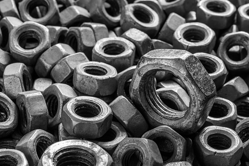 Lots of iron nuts. Old nuts close up. Black and white image. Selective focus.