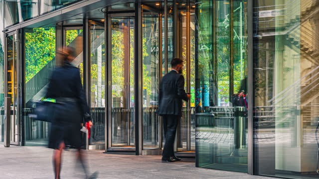 Time lapse of Business people entering and leaving office building via automatic Revolving Door in downtown district of London