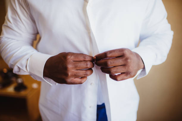 Businessman buttoning up his dress shirt White button up dress shirt with man buttoning buttoning stock pictures, royalty-free photos & images