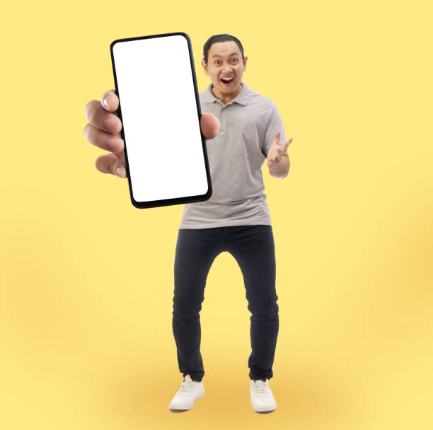 istock Asian man looking to camera, smiling and showing empty blank white copy space phone mock up template 1482984615