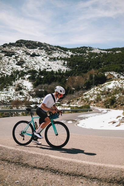 istock Road cyclist rides up snowy mountain road 1482984724