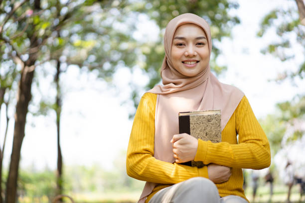 istock Muslim woman reading a book in a park. 1482987733