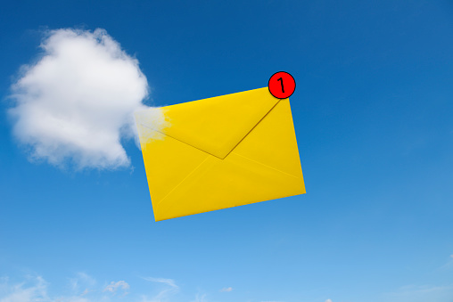 Close-up of E-mail envelope in clouds with notification against blue sky.