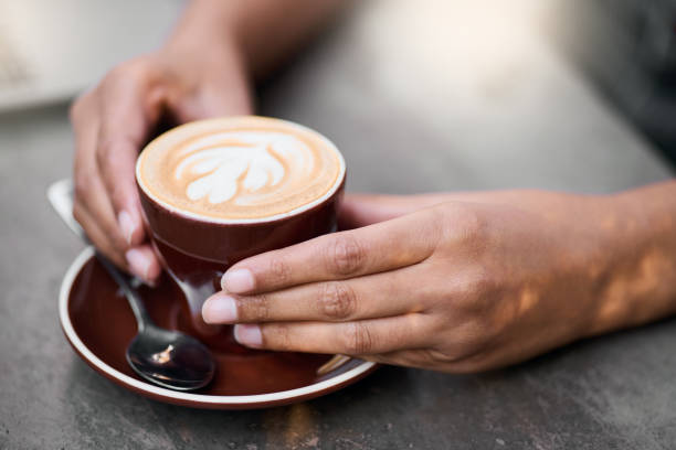 istock Coffee cup, hands on table with art for customer services, restaurant creativity and hospitality industry with inspiration. Cafe shop with person hand holding espresso, cappuccino or latte drink 1482990888