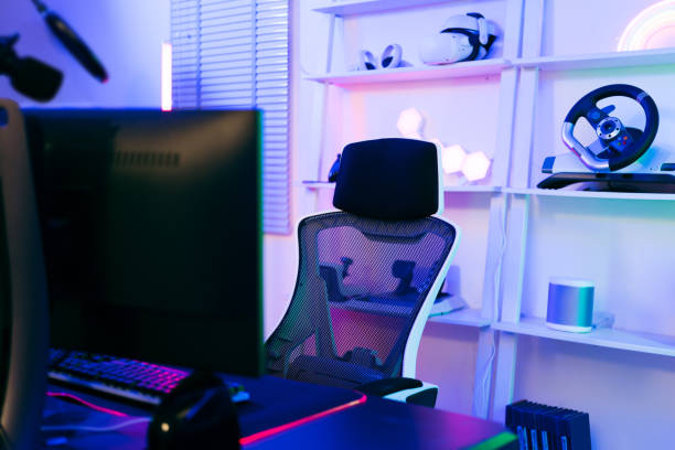 istock Darkroom for a professional gamer with a comfortable empty gamer chair, computer table, neon lights, keyboard, monitor, controllers and microphone for recording podcasts and live streaming at home. 1482991003